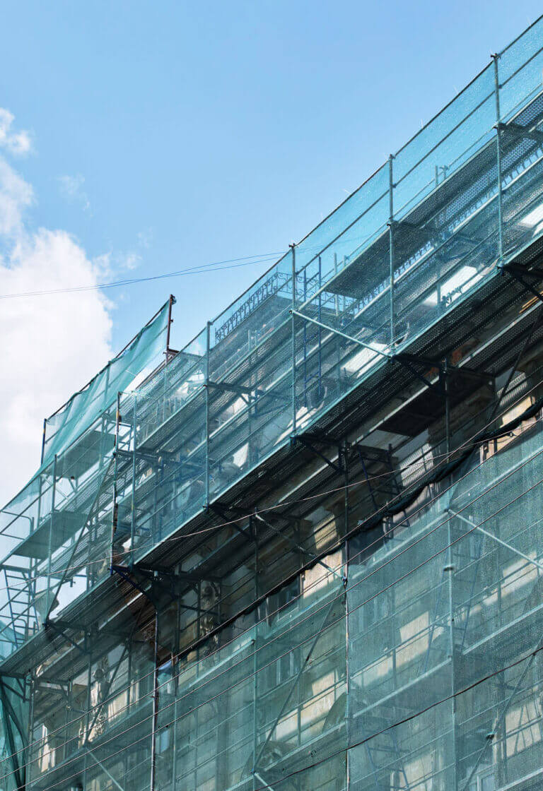 lešení se sítí při zateplování bytového domu