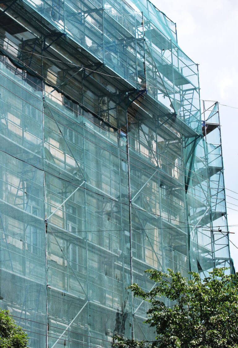 lešení se sítí při zateplování bytového domu